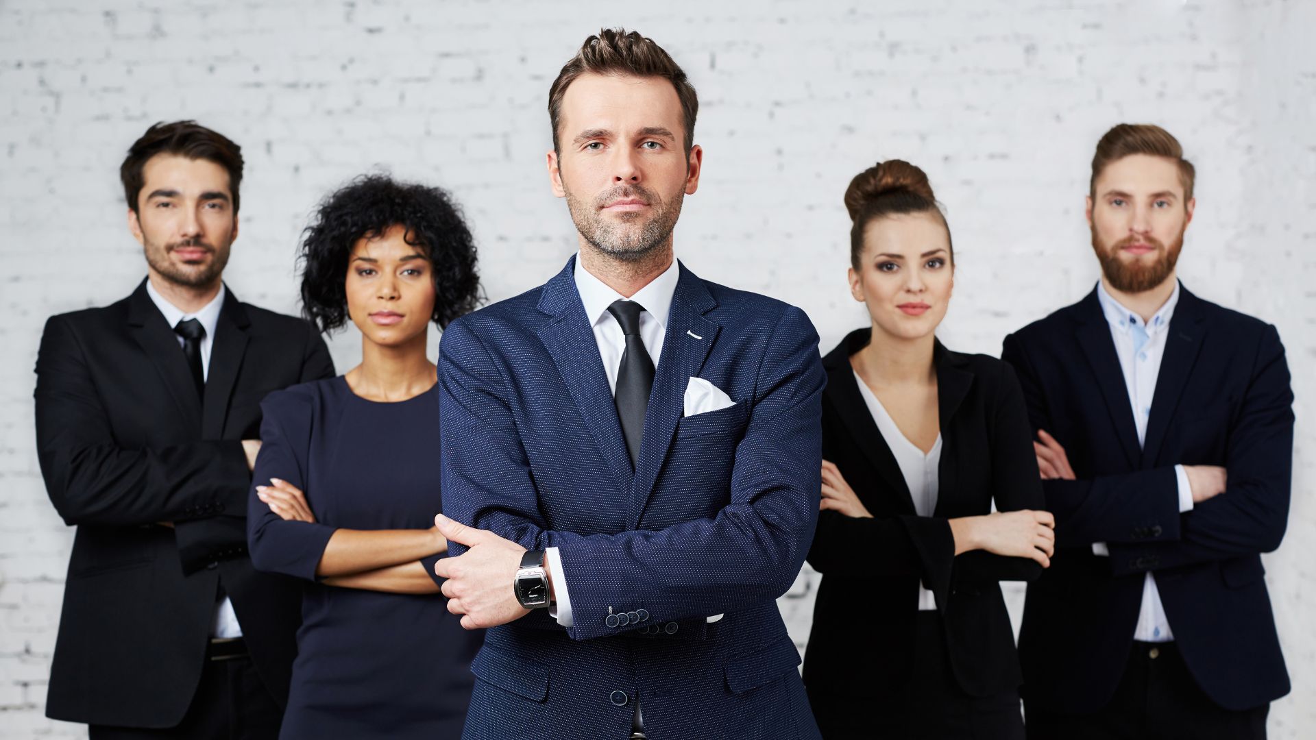 5 individuals from the legal profession, formally dressed, standing in a row with their arms crossed in front of them