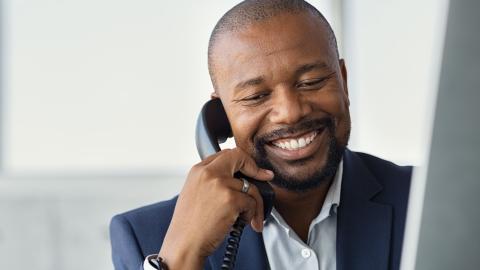 a professional man speaking on the phone in front of his computer, another place where good communication skills are an asset to you