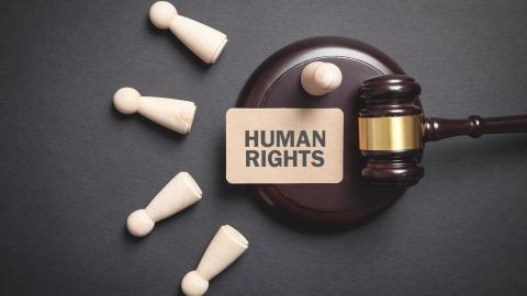 A hammer and gavel with a sign on saying human rights, tools commonly encountered by human rights lawyers