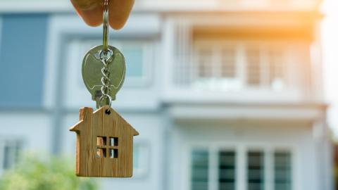 A hand holding out the keys to a house after the lease agreement has been signed